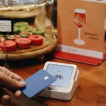 A person holding a card in front of a display of wine glasses